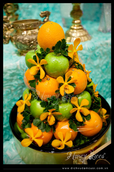Mâm ngũ quả thông thường được cách tân thành mâm trái cây gồm cam vàng và táo xanh cùng theme màu với các trang trí.